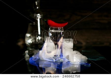 A Shot Of Vodka, An Alcoholic Beverage, Next To Ice, Fire, Ice, Red Chili Pepper. The Concept Of Alc