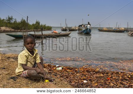 Cacheu, Republic Of Guinea-bissau - February 1, 2018: Young Boy Playing Next To The Water In The Por