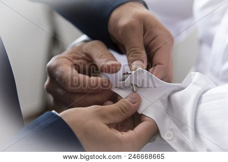 A Groom Putting On Cuff-links As He Gets Dressed In Formal Wear. Groom's Suit