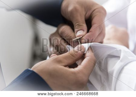 A Groom Putting On Cuff-links As He Gets Dressed In Formal Wear. Groom's Suit