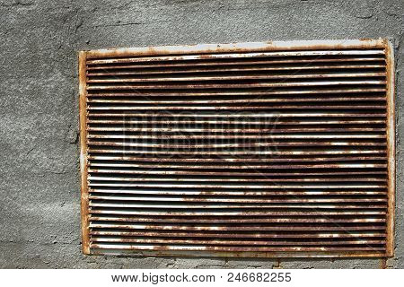 A Brick Wall With A Rusty Iron Grille In It