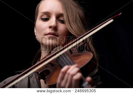 Young Woman With Half Of Her Hair Shaved While Playing A Baroque Violin On A Black Background
