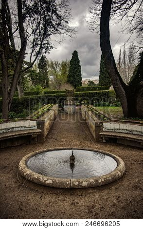 Small round fountain in a garden in a winter day with overcast sky