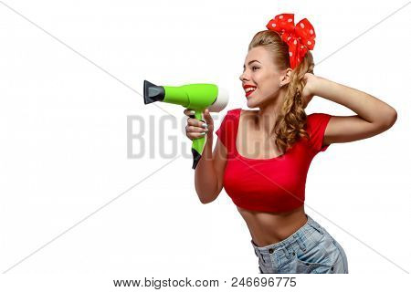 Half body portrait of young woman in pinup clothes with hairdryer makes attations