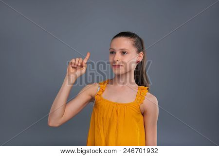 Excuse Me. Charming Teenage Girl Raising Her Finger And Attracting Someones Attention While Standing