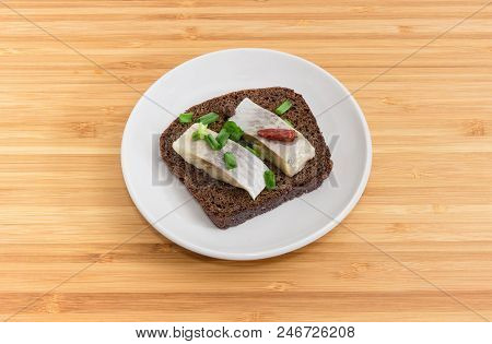Open Sandwich Made Of Brown Bread, Slices Of Fillet Of Pickled Atlantic Herring, Hot Pepper And Gree