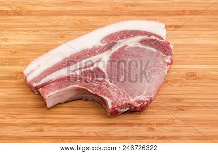 Uncooked Pork Loin Chop With Rib On The Bamboo Cutting Board