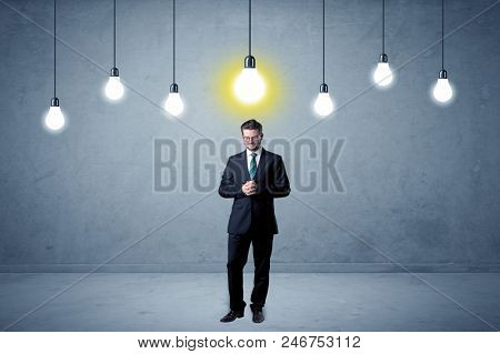 Handsome businessman in an empty space with bulbs above and uninspired face