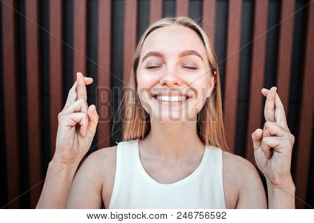 Happy And Positive Blonde Girl Is Standing And Keeping Her Eyes Closed. She Is Smiling. Young Woman 