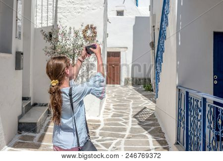 Gorl taking photo of rustic Greek architecture