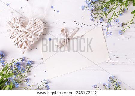 Empty Tag  With Bow, Rame  From  Blue Forget-me-nots Or Myosotis Flowers And Heart On  White Wooden 