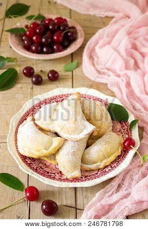 Pies With Cherries, Sprinkled With Powdered Sugar And Berries Of Fresh Cherries On A Wooden Surface.