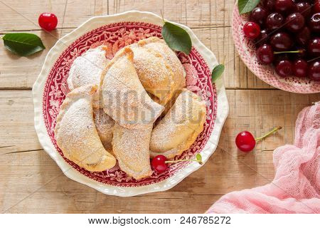 Pies With Cherries, Sprinkled With Powdered Sugar And Berries Of Fresh Cherries On A Wooden Surface.