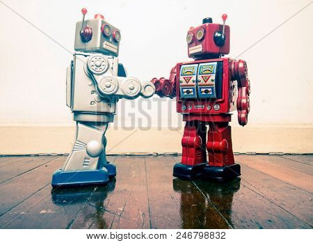 two vintage robot shake hands on a old wooden floor  toned image 