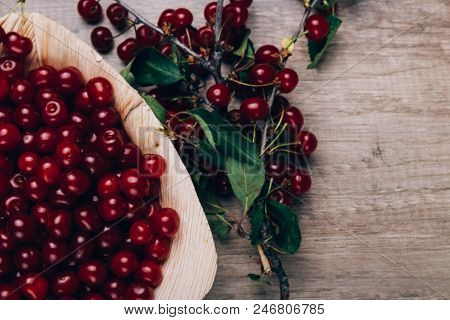 Fresh Red Cherries In A Wooden Plate On A Wooden Table. Wooden Plate On A Wooden Background. Next To