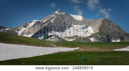 Tourist Tent On Green Grass Against The Background Of High Mountains. Lago-naki. Russia