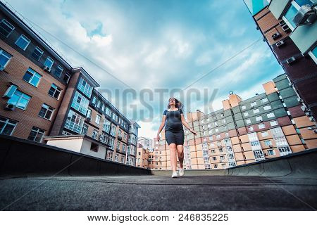 Beautiful Young Pregnant Woman Walking Through The City Streets. Concept Of Motherhood And Pregnancy
