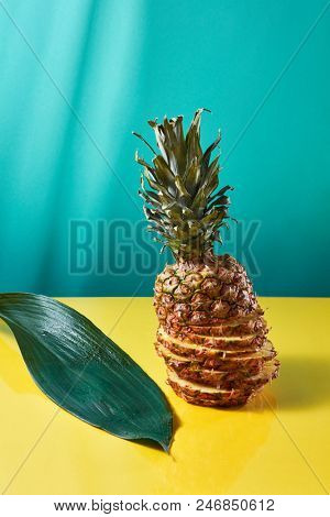 Whole pineapple sliced and reassembled on colored background