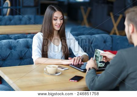 A Young Professional Is Sitting While A Man Opposite Her Is Counting A Great Sume Of Dollars.