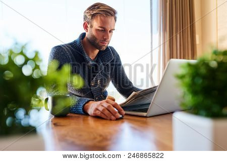 Handsome Modern Man Busy Reading The Newspaper And Checking His Mails To Catch Up On Current Affairs