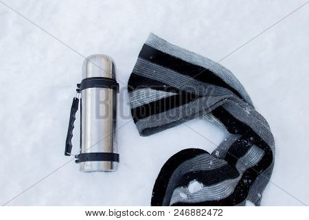 Steel Thermos, Near The Grey-black Striped Scarf On The Snow Surface