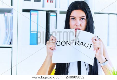 Young Angry Female Office Worker Ripping Contract At The Desk.