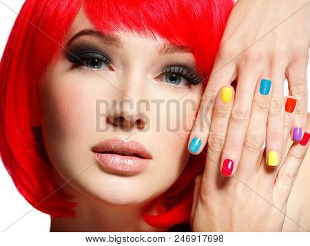 Closeup face of a beautiful  girl with bright multicolor nails. Gorgeous and stunning  woman with bob hairstyle red color. 