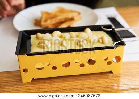 Swiss Food. Cheese Raclette With Mushrooms On Coupelles - Special Small Skillet For A Raclette