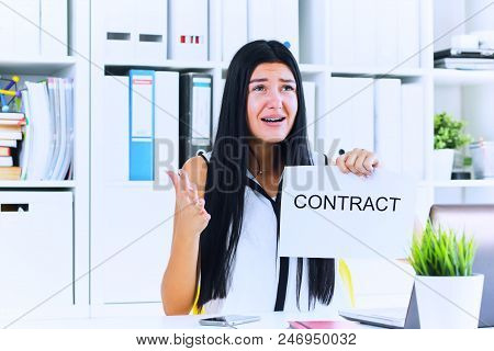 Young Unhappy Female Office Worker Ripping Contract At The Desk.
