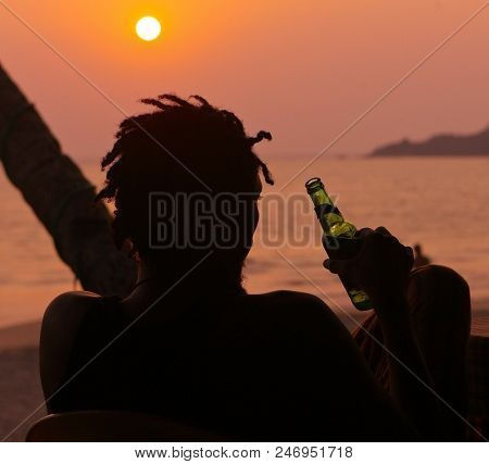A Dredlocked Man Chilling And Drinking Beer On The Sunset, Goa, Arambol, India