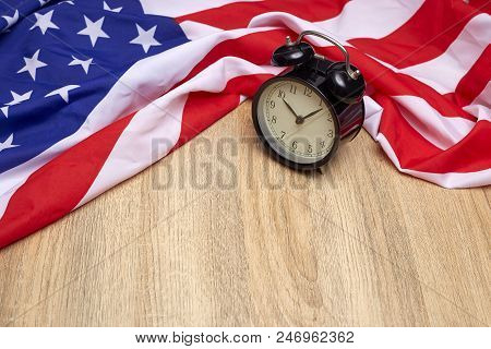 National flag of America and black alarm clock on old wooden background