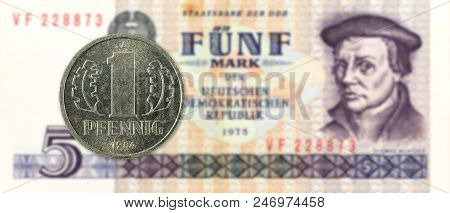 1 Pfennig Coin Against Historic 5 East German Mark Bank Note