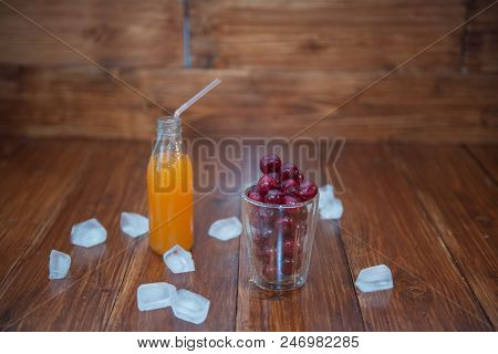 Sweet Cherry, Black Cherries In A Glass On Wooden Background With Fresh Juicy In Glass Bottle. Ice A