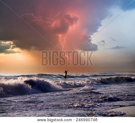 Silhouette of surfers on wave, stormy sky in the background
