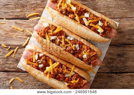Authentic Chili Hot Dog With Cheddar Cheese, Onion And Spicy Sauce Close-up On Paper. Horizontal Top