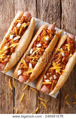 Authentic Chili Hot Dog With Cheddar Cheese, Onion And Spicy Sauce Close-up On Paper. Vertical Top V
