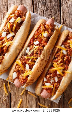 Chili Hot Dog With Cheddar Cheese And Spicy Sauce Close-up. Vertical Top View From Above