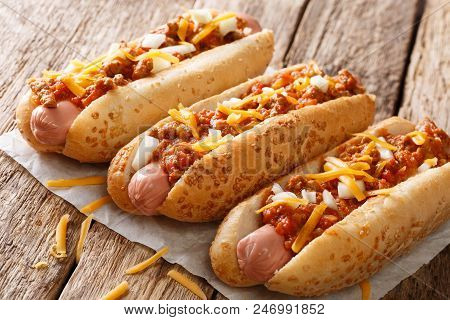 Traditional American Chili Hot Dogs With Cheddar Cheese, Onion And Spicy Sauce Closeup. Horizontal