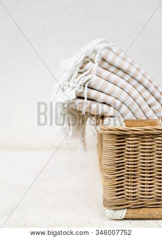 White Stripe Cotton Bath Towels Lying In Whicker Basket On White Background. Organic Pestemal Towels