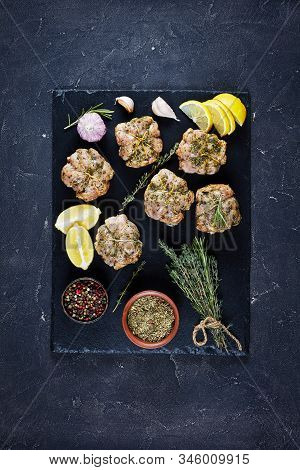 Raw Rabbit Ballotine Prepared To Be Cooked On A Black Slate Plate With Herbs And Spices,  Vertical V