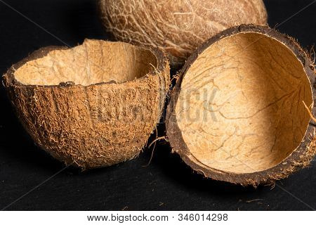 Two Halves Of Coconut Shell And Inner Soft Walnut On Black Stone