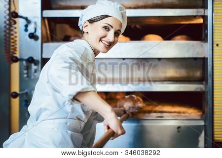 Baker putting bread in the bakery oven cowering on the floor of the bakery