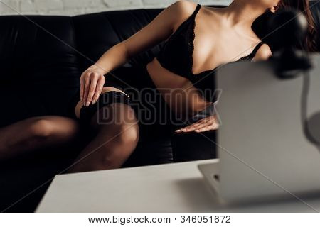 Cropped View Of Seductive Woman In Bra And Skirt Taking Off Stocking While Posing At Web Camera Of S