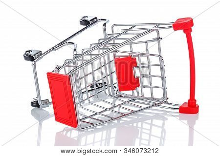 Lying On Its Side Empty Chromed Toy Market Shopping Cart With Red Handle And Plastic Board On The Fr