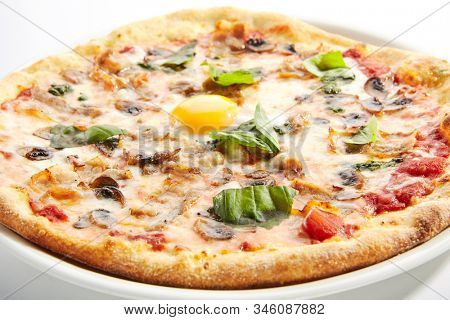 Pizza with mushrooms, bacon and egg on white restaurant plate isolated. Italian carbonara pizza with mushrooms, tomatoes and fresh green basil closeup