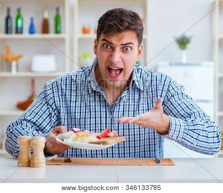Young husband eating tasteless food at home for lunch