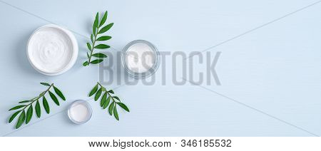Jars Of Organic Cosmetic Cream And Green Leaves On Blue Background. Organic Natural Cosmetic Product