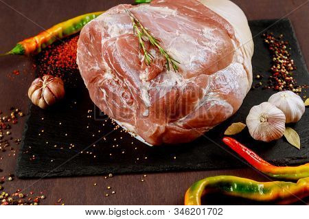 Raw Pork Shoulder With , Garlic And Bay Leaf On Black Stone Board.