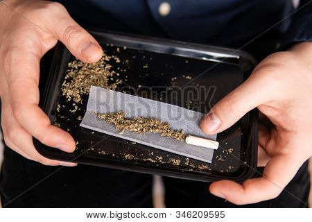 Preparing A Joint And Drug Paraphernalia Concept Theme With Close Up Man Hands Rolling A Joint With 