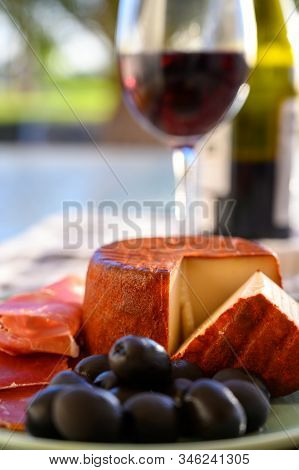 Tastes Of Spain, Jamon Iberian, Black Olives, Manchego Cheese With Red Paprika And Glass With Red Ri